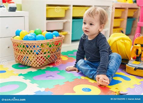 Adorable Blond Toddler Sitting On Floor With Relaxed Expression At