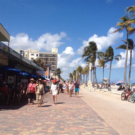 people walking down the street in front of shops and palm trees on a ...