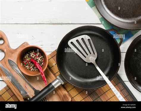 Several Empty Cast Iron Frying Pans On A White Wooden Background View