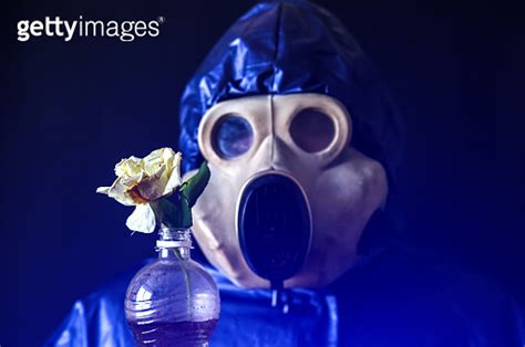 Man In The Gas Mask Holding Plastic Bottle With Dirty Water And Flower