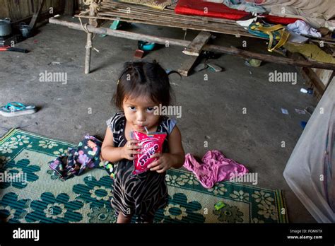 A Young Girl Living In Poverty Drinks A Refreshment In Her Wood Home In