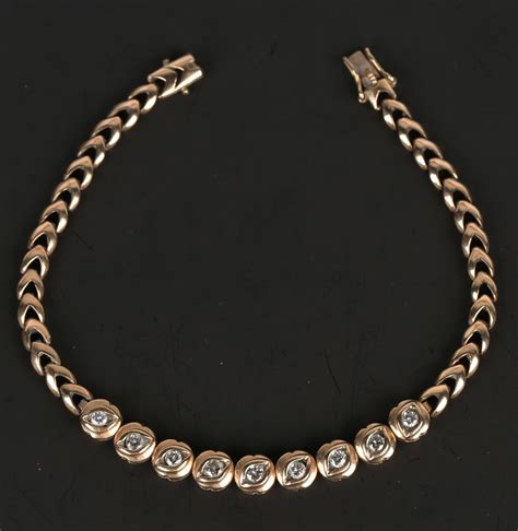 A gold and diamond bracelet, the front mounted with a row of nine ...