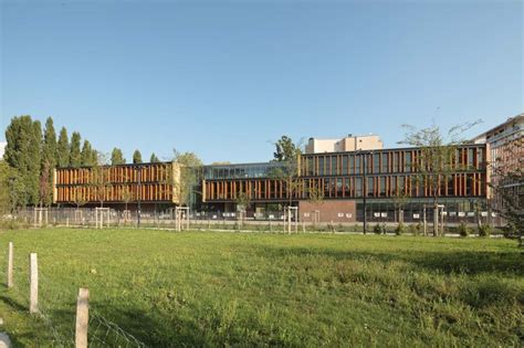 A Large Building With Many Windows In The Middle Of A Grassy Field Next