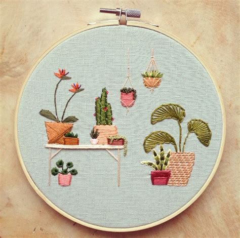 An Embroidery Project With Potted Plants On A Table And Hanging