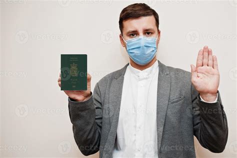 European Man In Formal Wear And Face Mask Show Faroe Islands Passport With Stop Sign Hand