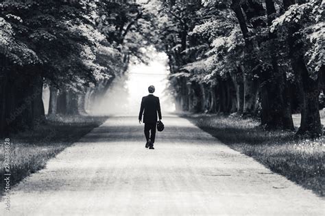 Black And White Photo Of A Businessman Or Gentleman In A Suit Walking