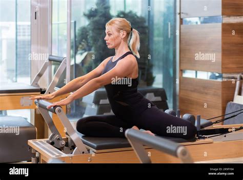 Active Blonde Woman Strengthening Abdominal And Leg Muscles On Reformer