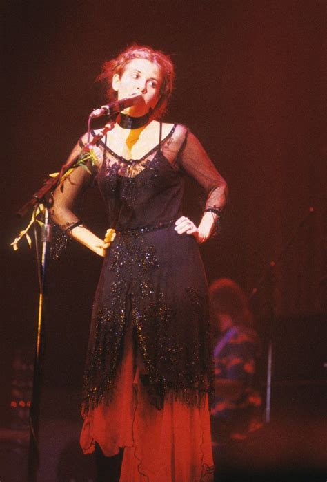 A Woman Standing In Front Of A Microphone On Stage