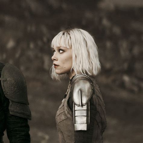 a woman with white hair and armor standing next to a man in black leathers