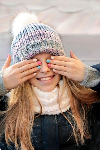 La Jeune Fille Sourit Joyeusement Couvrant Ses Yeux Avec Ses Mains