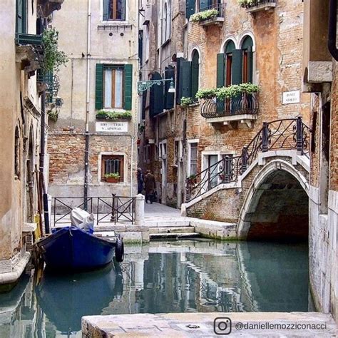 A Small Boat Is In The Water Near Some Buildings And A Bridge With