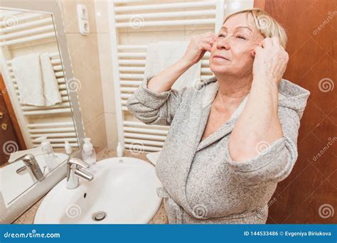 Senior Woman Touching Her Soft Face Skin And Does Massage Looking In