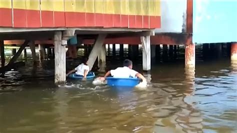 En cubetas así navegan estos niños un río para poder ir a la escuela