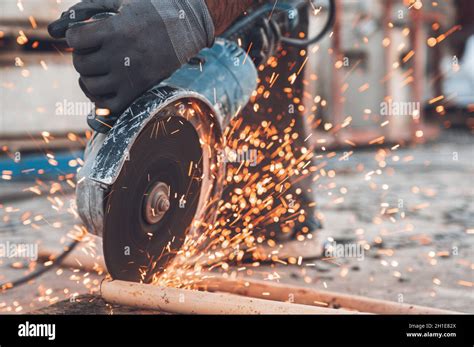 Construction Worker Using Angle Grinder Cutting Metal At Construction