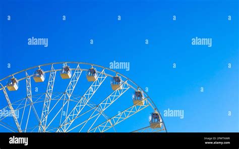 Panoramic Ferris Wheel Carousel With Cabins Spinning Against A Blue Sky