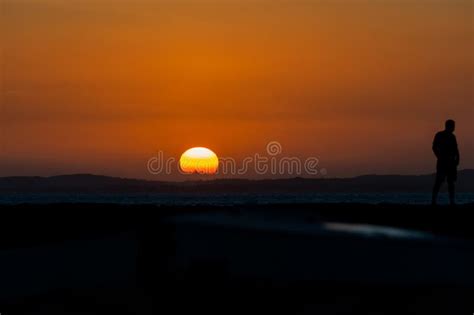 A Person In Silhouette Is Seen On The Porto Da Barra Pier Enjoying