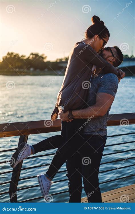 Man Lifting Up And Kissing His Girlfriend In A Sunset Stock Photo