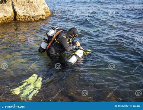 People In Wetsuits And Scuba Gear Are Preparing To Dive Into The Water