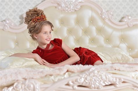 Premium Photo | Cute little girl in red dress lying on bed 