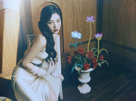 A Woman Sitting Next To A Vase With Flowers In It