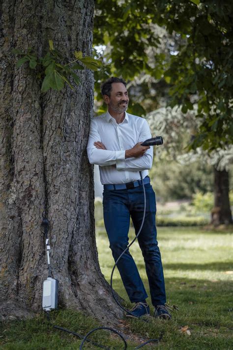 Lächelnder Geschäftsmann mit verschränkten Armen der ein Ladekabel