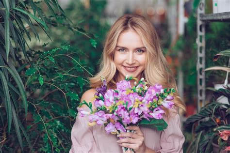 Blonde Jeune Femme Tenant Un Bouquet De Fleurs Mauves En Mains Photo Gratuite