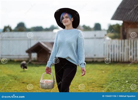 Young Beautiful Girl In A Village Holding A Basket With Chicken Eggs