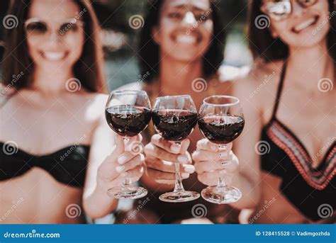 Mujeres Sonrientes Jovenes Que Beben El Vino En El Poolside Foto De