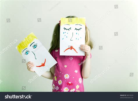 Little Blonde Girl Holding Happy And Sad Face Masks Symbolizing