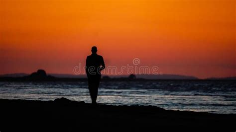 Silhouette of a Man Walking on the Beach at Sunset. Stock Photo - Image ...