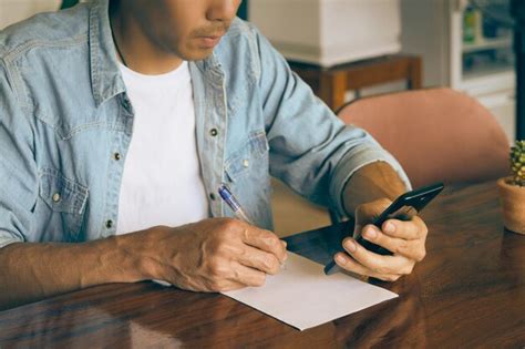 Premium Photo Midsection Of Man Holding Paper While Sitting On Table