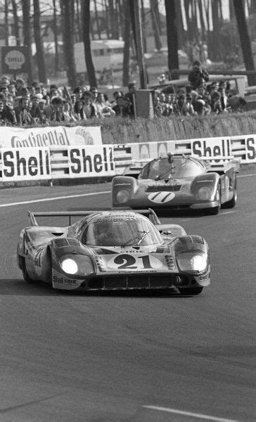 Two Race Cars Racing On A Track With People Watching