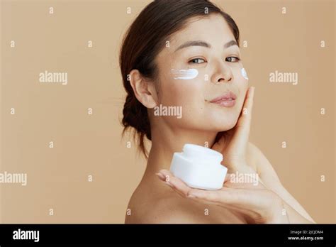 Modern Woman With Facial Cream Jar And Facial Cream On Face On Beige