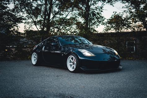 Black Car with White Wheels Parked on Asphalt Road · Free Stock Photo