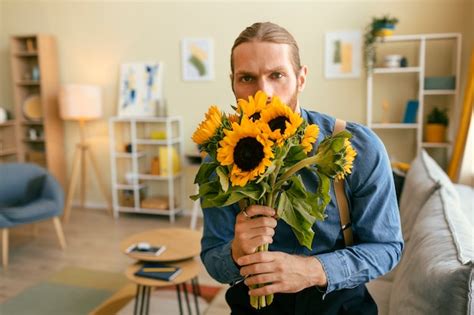 Free Photo Portrait Of Bearded Man Smelling Bouquet Of Sunflowers