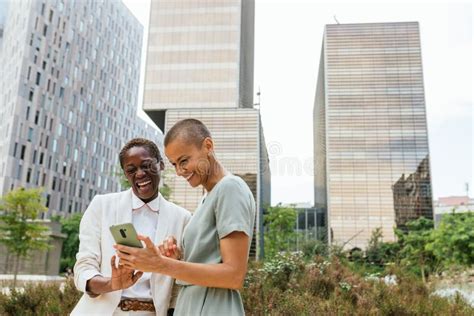 Two Businesswomen In A Park In Front Of Business Buildings