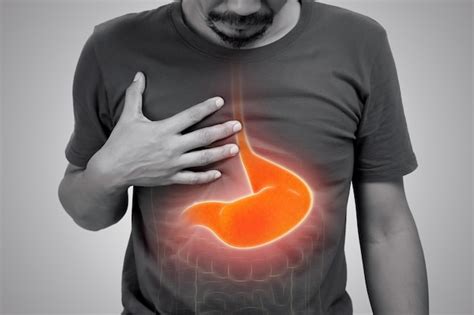 Hombre asiático que sufre de gastritis sobre fondo gris Foto Premium