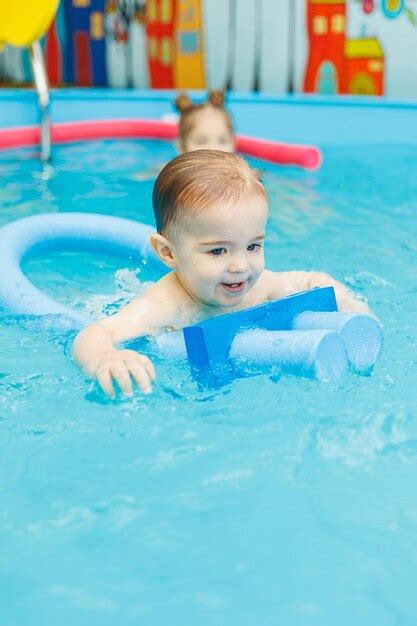 Um Menino De 2 Anos Aprende A Nadar Em Uma Piscina Um Treinador