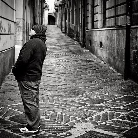 Black And White Photograph Of A Man Walking Down An Alleyway