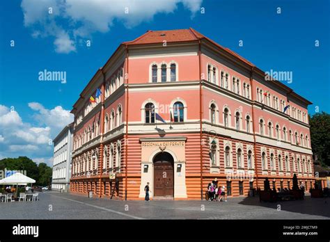 Imposing Red Building With Columns And Arched Windows A Small Group Of