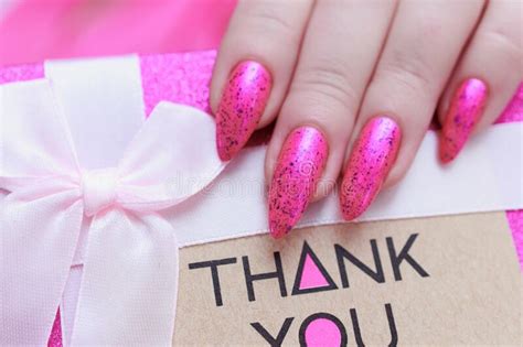 Female Hands With Long Nails And Pink Nail Polish Hold A Picture With