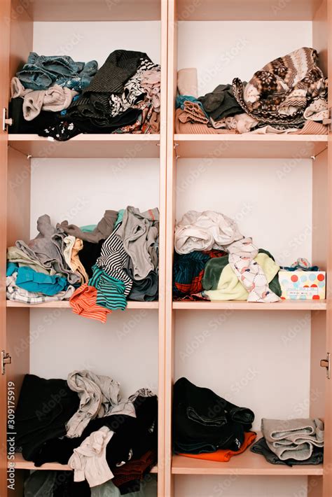 Messy Wardrobe Shelves Piles Of Unfolded Clothes In A Closed Rack Clutter On Home Furniture