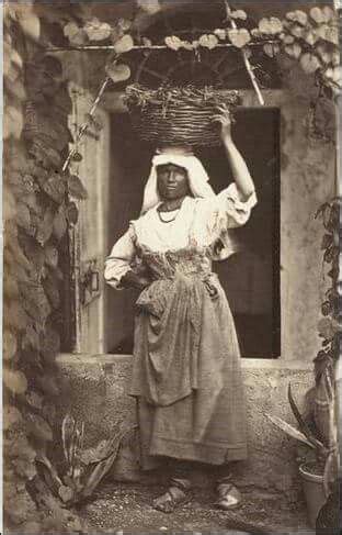 An Old Black And White Photo Of A Woman With A Basket On Her Head