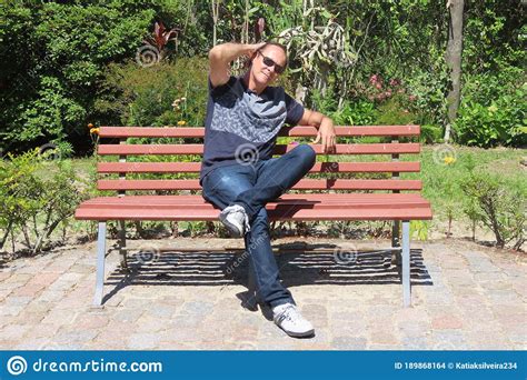 Hombre Encantador Sentado En Un Banco De Un Parque Con Gafas De Sol