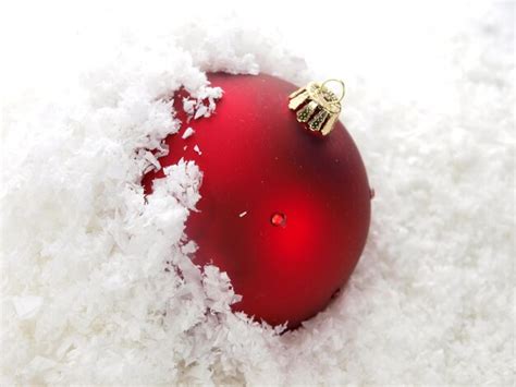 Premium Photo | A red ornament in the snow with the word christmas on it.