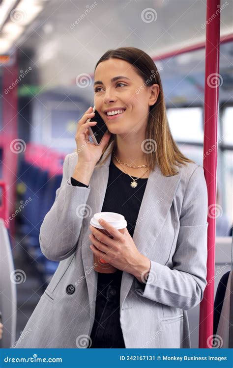 Standing Businesswoman With Takeaway Coffee Commuting To Work On Train