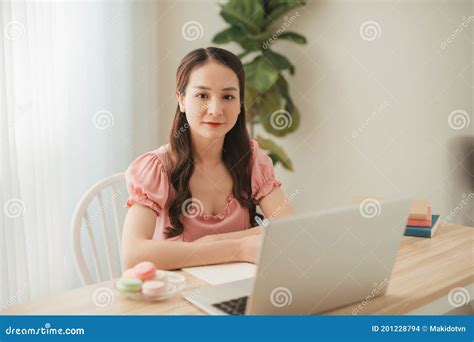 Smiling Asian Woman Working With Laptop On Table In White Interior Home