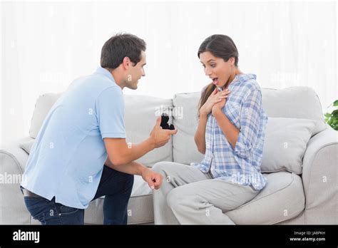 Man On Bended Knee Offering An Engagement Ring To His Partner On The