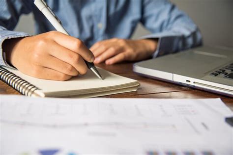 Premium Photo Midsection Of Businessman Writing In Book With Laptop