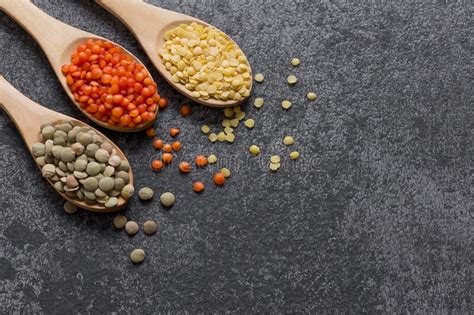 Red Green And Yellow Lentils In Wooden Spoon On Grey Rustic Background